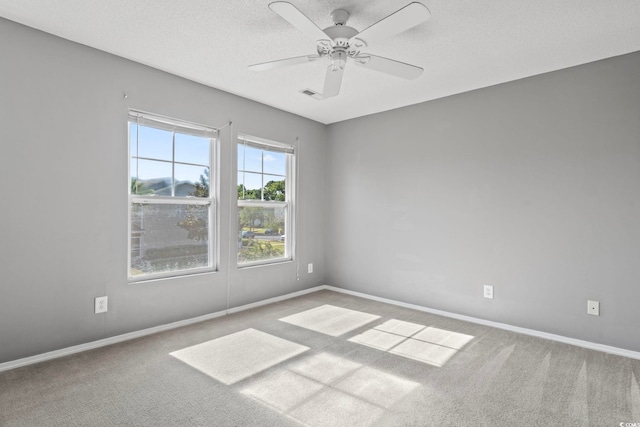 empty room with ceiling fan, a textured ceiling, and light carpet