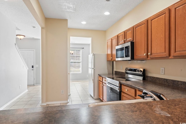 kitchen featuring appliances with stainless steel finishes, a textured ceiling, sink, and light tile patterned floors