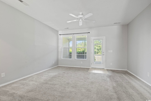 empty room with light carpet, ceiling fan, and a textured ceiling