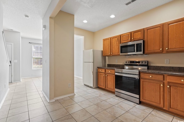 kitchen featuring a textured ceiling, appliances with stainless steel finishes, and light tile patterned floors