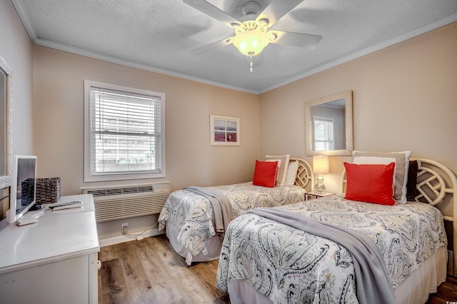 bedroom with ceiling fan, a textured ceiling, light hardwood / wood-style flooring, crown molding, and an AC wall unit