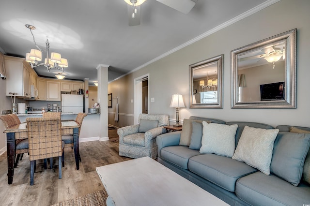 living room featuring ceiling fan with notable chandelier, light wood-type flooring, and ornamental molding