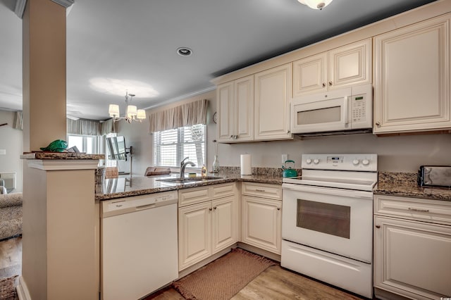 kitchen with kitchen peninsula, white appliances, cream cabinetry, a notable chandelier, and light wood-type flooring