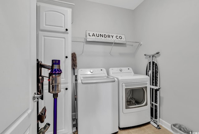 clothes washing area featuring washer and clothes dryer and light tile patterned floors