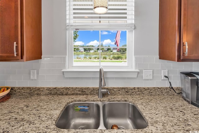 details featuring light stone countertops, sink, and tasteful backsplash