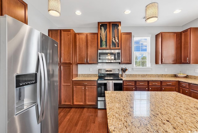 kitchen featuring light stone countertops, appliances with stainless steel finishes, dark hardwood / wood-style flooring, and decorative backsplash