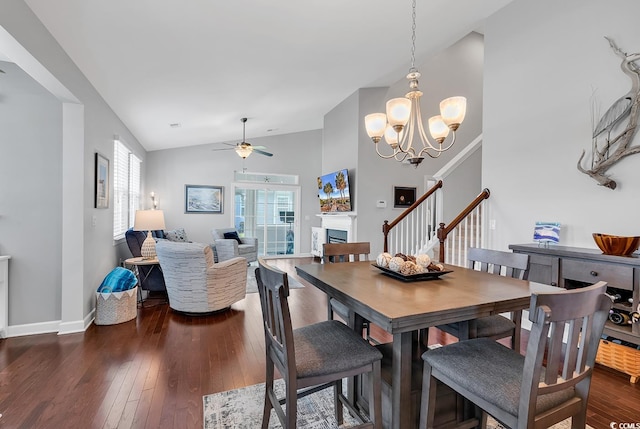 dining space with lofted ceiling, ceiling fan with notable chandelier, and dark hardwood / wood-style flooring