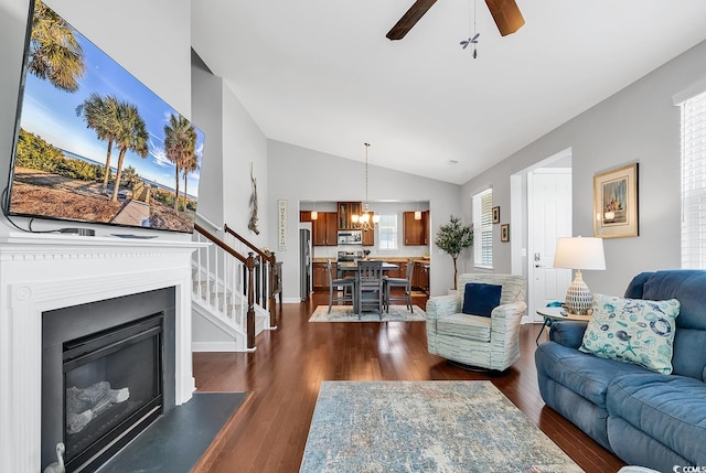 living room with ceiling fan with notable chandelier, vaulted ceiling, and dark hardwood / wood-style floors