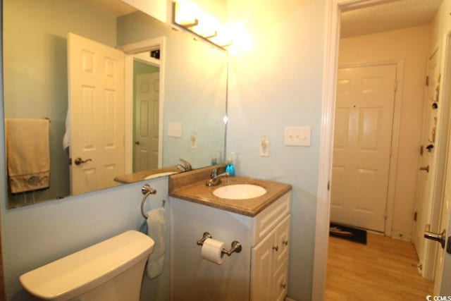 bathroom featuring wood-type flooring, vanity, and toilet