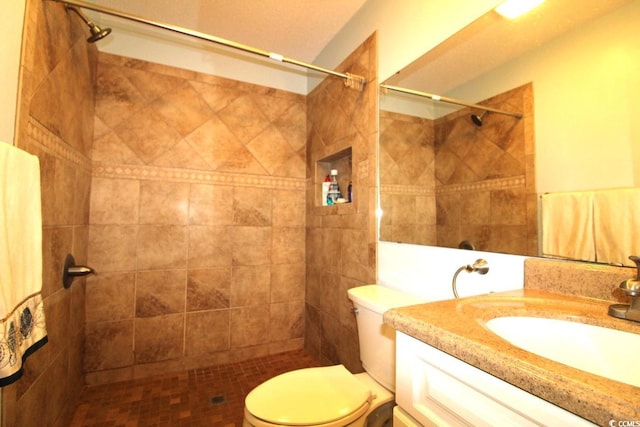 bathroom featuring vanity, toilet, and a tile shower