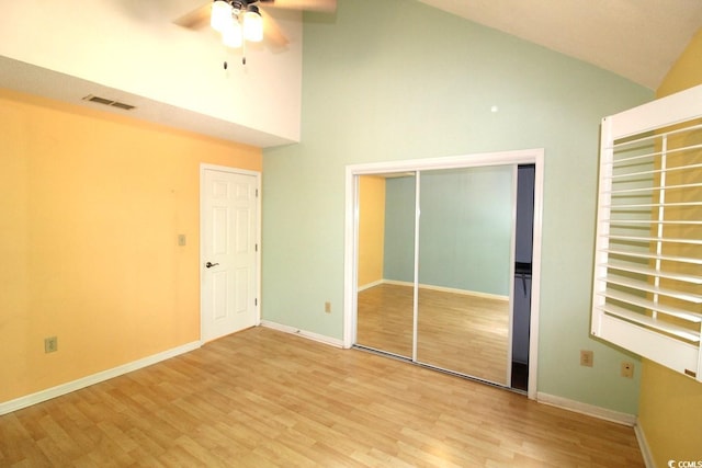 unfurnished bedroom featuring hardwood / wood-style flooring, ceiling fan, a closet, and high vaulted ceiling