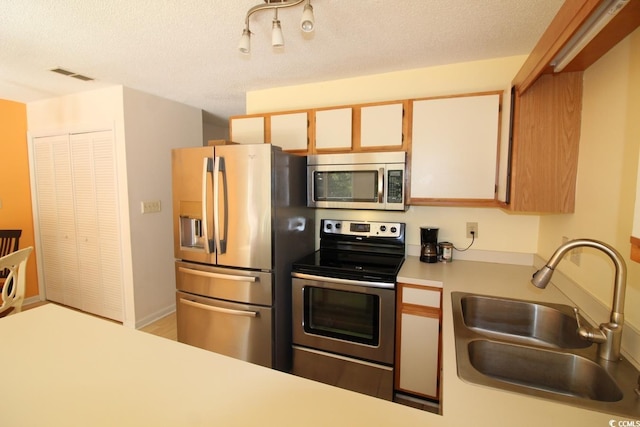 kitchen featuring a textured ceiling, appliances with stainless steel finishes, white cabinetry, and sink