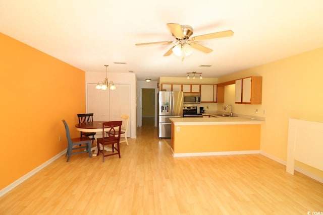 kitchen featuring stainless steel appliances, sink, light hardwood / wood-style flooring, and kitchen peninsula