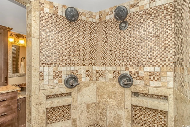 bathroom featuring tiled shower and vanity