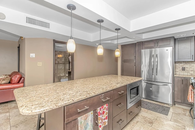 kitchen featuring light stone counters, a kitchen breakfast bar, a kitchen island, and stainless steel appliances