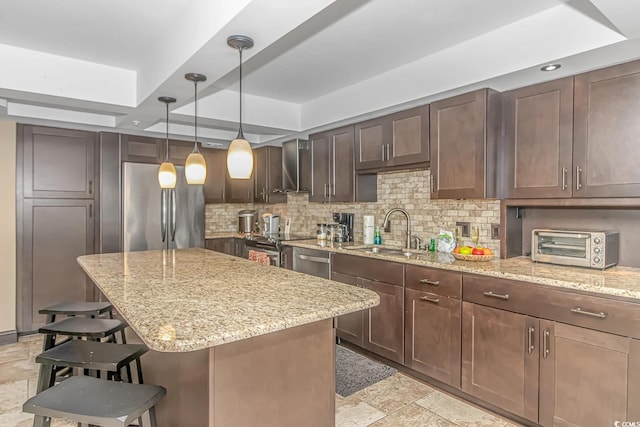 kitchen featuring a kitchen island, a breakfast bar area, light stone countertops, stainless steel appliances, and sink