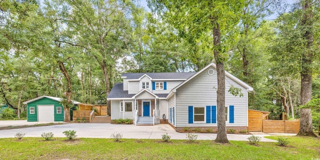 view of front facade featuring a front yard, an outbuilding, driveway, and fence