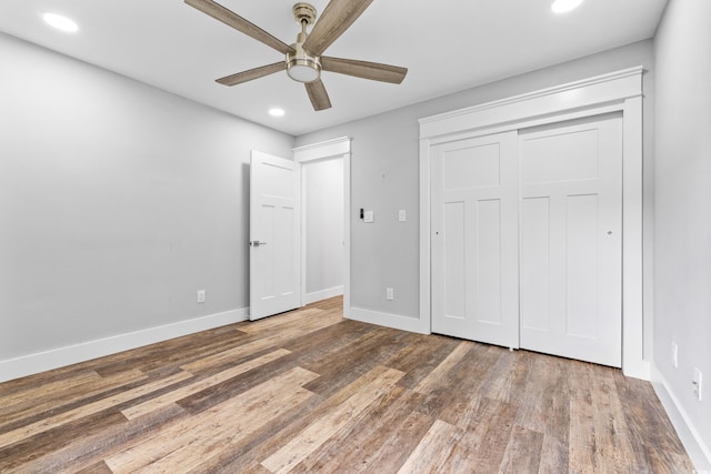 unfurnished bedroom featuring a closet, baseboards, wood finished floors, recessed lighting, and a ceiling fan