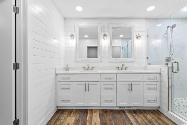 bathroom with wooden walls, a shower with door, vanity, and hardwood / wood-style flooring