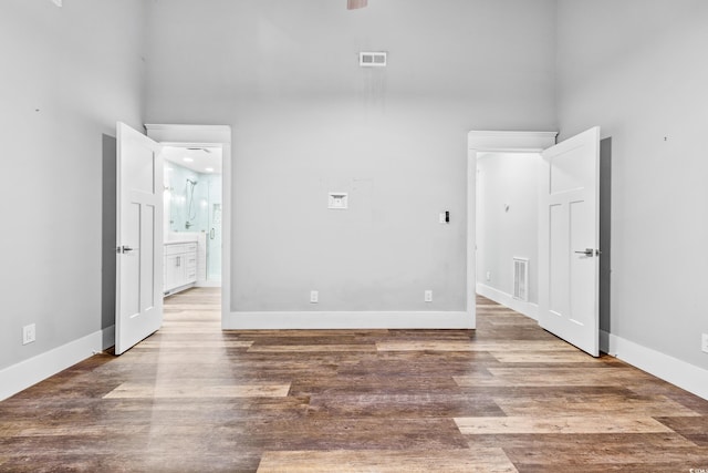 unfurnished bedroom with a high ceiling, visible vents, and wood finished floors