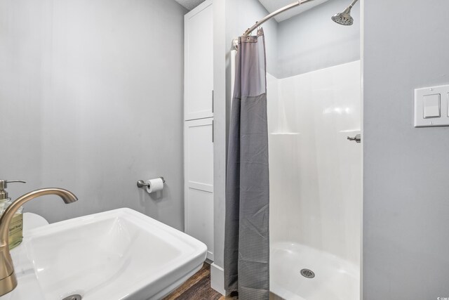 bathroom with a stall shower, wood finished floors, and a sink