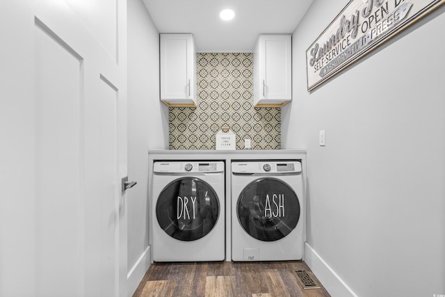 clothes washing area with cabinets, dark wood-type flooring, and washer and dryer