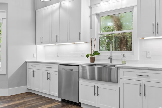 kitchen with light countertops, dark wood-type flooring, a sink, dishwasher, and white cabinets