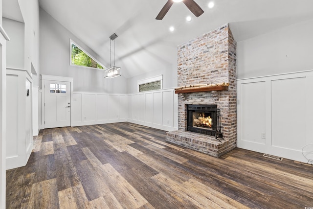 unfurnished living room featuring ceiling fan, a brick fireplace, dark hardwood / wood-style flooring, and high vaulted ceiling