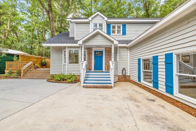 view of front of house featuring brick siding and roof with shingles
