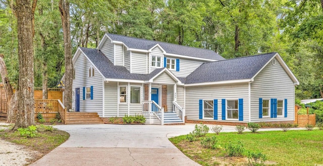 view of front of home featuring driveway, a shingled roof, and a front lawn