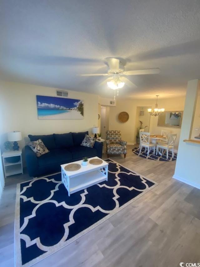 living room featuring ceiling fan with notable chandelier and hardwood / wood-style floors