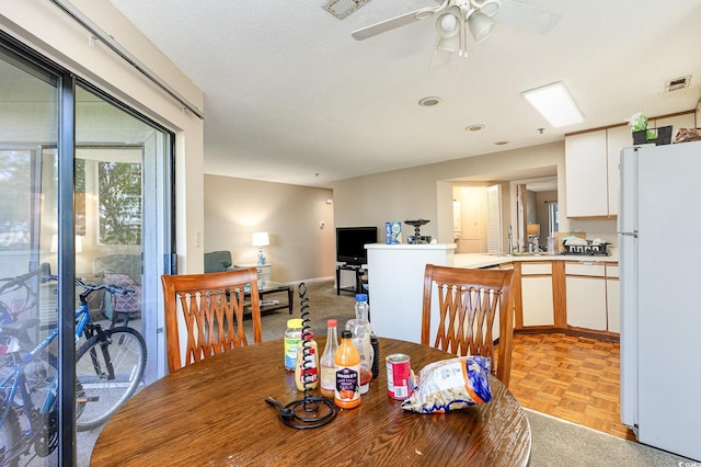 dining area with ceiling fan, a textured ceiling, and light parquet flooring