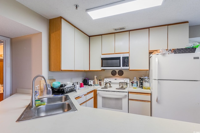 kitchen with white cabinets, white appliances, a textured ceiling, and sink