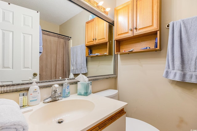 bathroom with vanity, toilet, a textured ceiling, and a shower with shower curtain