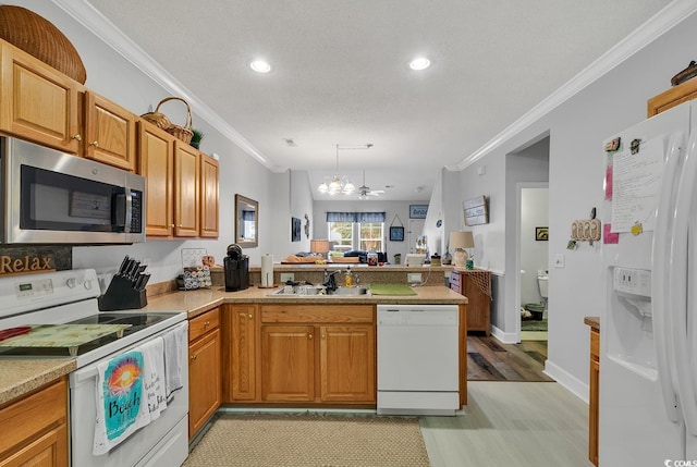 kitchen with kitchen peninsula, a notable chandelier, sink, and white appliances