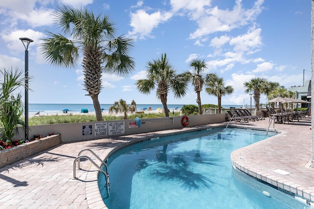 view of swimming pool featuring a water view and a patio