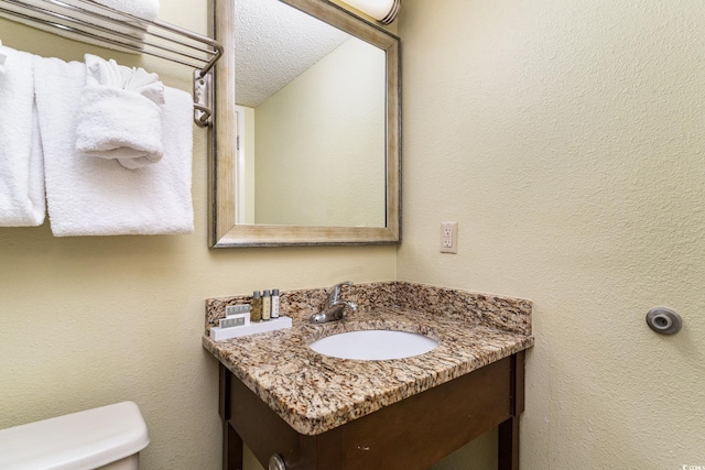 bathroom featuring a textured ceiling, vanity, and toilet