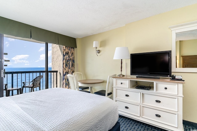 bedroom featuring a textured ceiling, a water view, access to exterior, and dark carpet