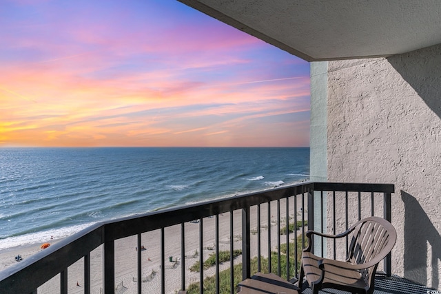 balcony at dusk featuring a water view