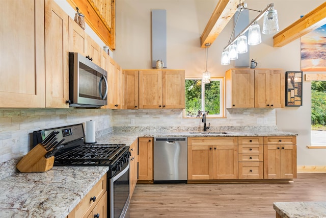 kitchen featuring backsplash, light brown cabinets, stainless steel appliances, and a sink