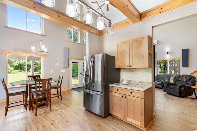 kitchen with stainless steel fridge with ice dispenser, light wood-style flooring, beamed ceiling, a high ceiling, and light brown cabinets