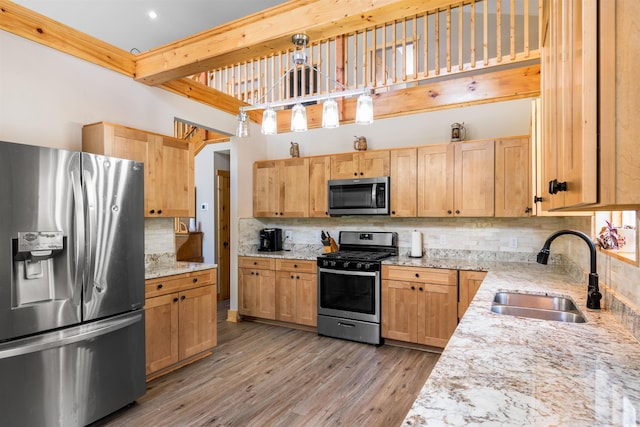 kitchen with decorative backsplash, beamed ceiling, stainless steel appliances, light wood-type flooring, and a sink