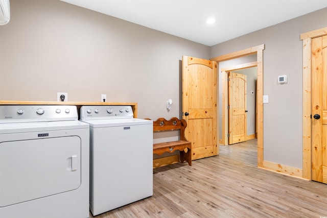 washroom featuring baseboards, a wall mounted AC, light wood-style flooring, and washer and dryer