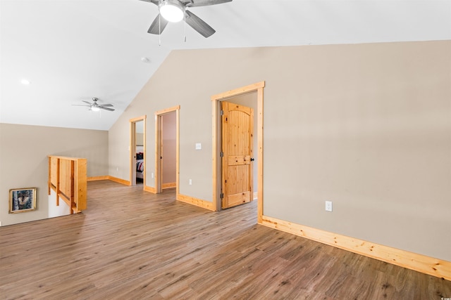 empty room with washer / clothes dryer, light wood-style floors, a ceiling fan, vaulted ceiling, and baseboards