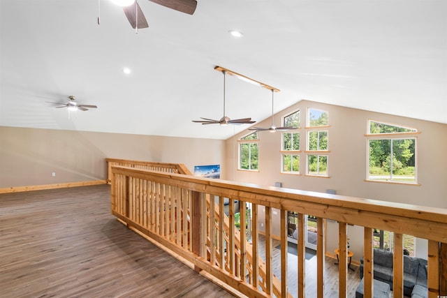 corridor featuring lofted ceiling, plenty of natural light, wood finished floors, and baseboards