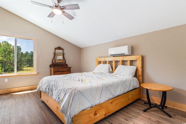 bedroom featuring wood finished floors, vaulted ceiling, baseboards, and a wall mounted AC