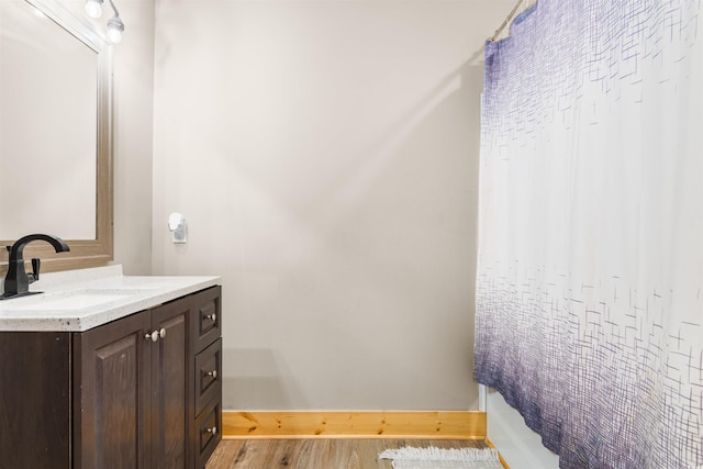 full bathroom with baseboards, wood finished floors, and vanity