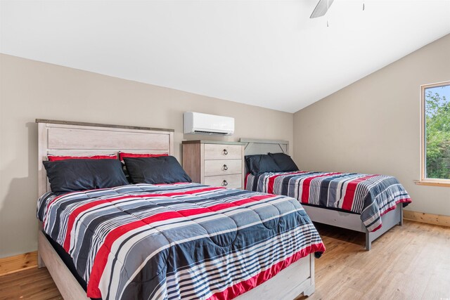 bedroom featuring lofted ceiling, an AC wall unit, ceiling fan, wood finished floors, and baseboards