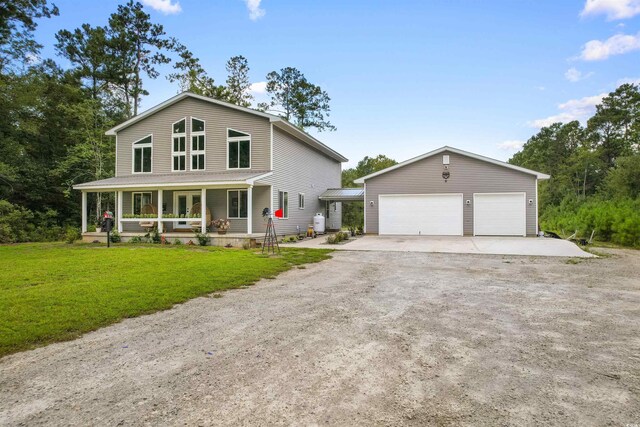 farmhouse featuring a porch, a front lawn, an outdoor structure, and a detached garage