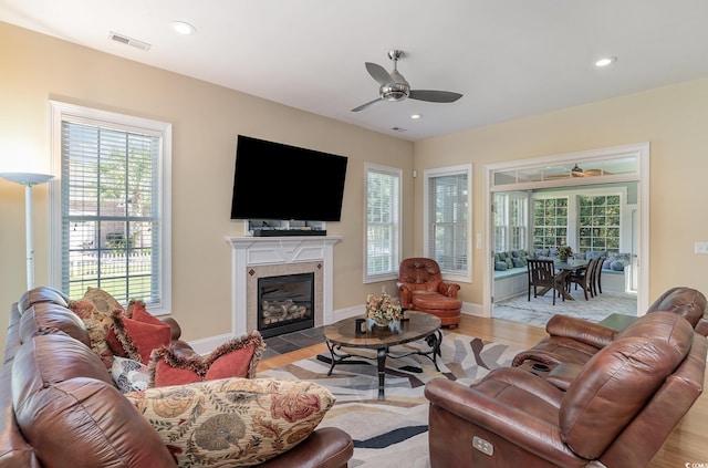 living room featuring a fireplace, ceiling fan, and light hardwood / wood-style flooring